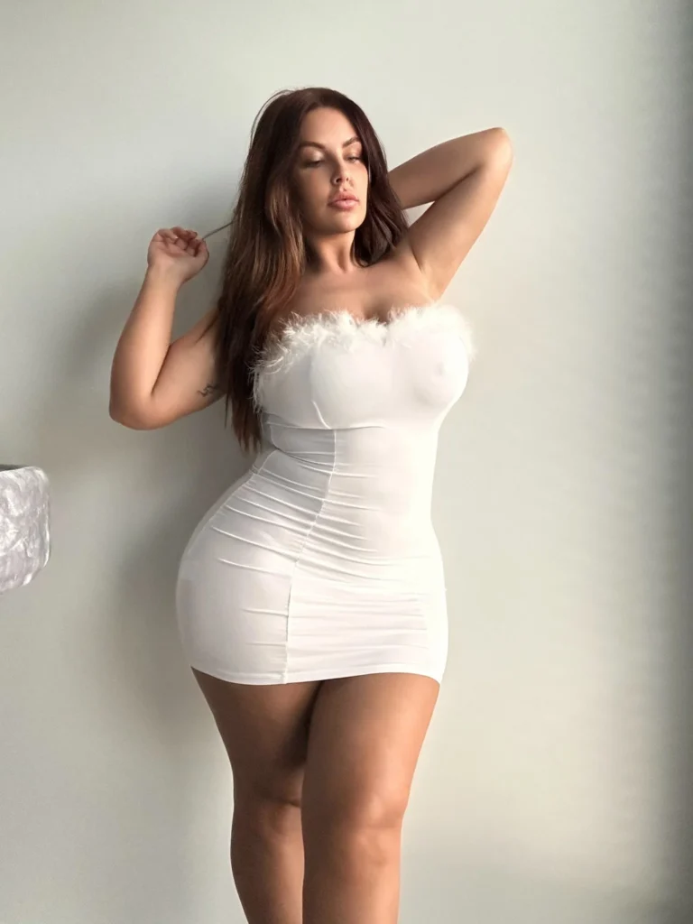 Shasha @curvyshasha OnlyFans-modelfoto staand in een witte strakke jurk